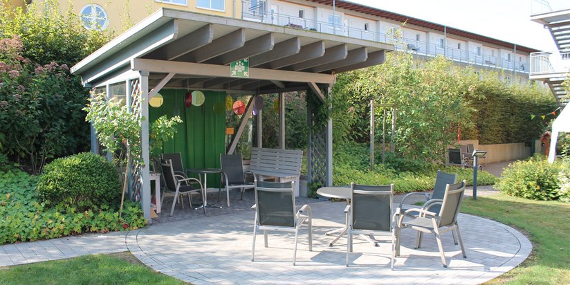 Gemütliche Sitzecke unter dem Rosenpavillon im hauseigenen Garten.