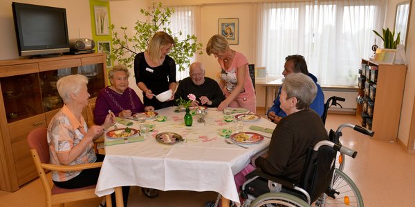 Zwei Mitarbeiterinnen bedienen die Bewohner beim gemeinsamen Mittagessen.