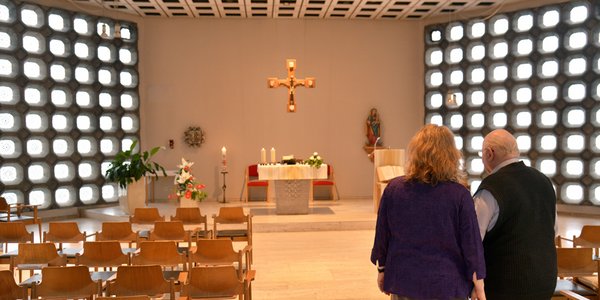 Eine Pflegerin besichtigt mit einem älteren Herren die Kapelle im Seniorencentrum. 